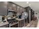 Sleek kitchen with stainless steel appliances, gray cabinets, mirrored backsplash, and modern fixtures at 25289 N 143Rd Dr, Surprise, AZ 85387