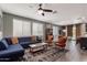 Open-concept living room with a blue sectional sofa, modern decor, and plenty of natural light at 25289 N 143Rd Dr, Surprise, AZ 85387