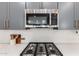 Gourmet kitchen featuring stainless steel appliances, sleek gray cabinetry, white backsplash, and modern gas cooktop at 3053 W Straight Arrow Ln, Phoenix, AZ 85083
