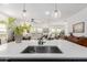 Bright kitchen with stainless steel sink, white countertops, pendant lights, and view of the living and dining areas at 3053 W Straight Arrow Ln, Phoenix, AZ 85083