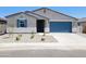 Charming single-story home with a blue garage door, desert landscaping, and nice window shutters at 37172 W Parador Ln, Maricopa, AZ 85138