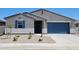 Charming single-story home with a blue garage door and desert landscaping in the front yard at 37172 W Parador Ln, Maricopa, AZ 85138