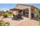 Back patio featuring pavers, an outdoor dining set, and desert landscaping at 41005 W Crane Dr, Maricopa, AZ 85138
