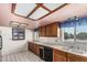 Traditional kitchen with wood cabinets, tile countertops, white tile floors, and unique patterned ceiling at 4402 W El Caminito Dr, Glendale, AZ 85302