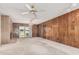 Spacious living room featuring a brick fireplace, wood paneled walls, and sliding glass door access at 4402 W El Caminito Dr, Glendale, AZ 85302