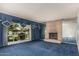 Bright living room features a brick fireplace, plush blue carpet, and large picture window at 4402 W El Caminito Dr, Glendale, AZ 85302