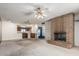 Spacious living room featuring brick fireplace, ceiling fans, and view of kitchen bar at 4402 W El Caminito Dr, Glendale, AZ 85302