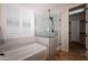 Bathroom with frameless glass shower enclosure and soaking tub with plantation shutters at 550 W Powell Way, Chandler, AZ 85248