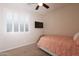 A bright bedroom with carpet, a ceiling fan, a television and a window with plantation shutters at 550 W Powell Way, Chandler, AZ 85248
