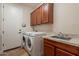 Well-equipped laundry room featuring a washer, dryer, ample cabinets, and a utility sink at 550 W Powell Way, Chandler, AZ 85248