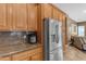 Kitchen featuring granite countertops, stainless steel refrigerator, and warm wood cabinets at 6840 S Crystal Way, Chandler, AZ 85249