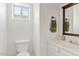 Bathroom features a toilet, wooden framed mirror and white cabinets at 706 N El Dorado Dr, Gilbert, AZ 85233