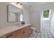 Bright bathroom with a wood countertop vanity, modern lighting, decorative mirror, and patterned tile floor at 733 W El Camino Dr, Phoenix, AZ 85021