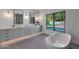 Modern bathroom featuring a freestanding tub, dual sinks, stylish tile work, and view to the pool at 733 W El Camino Dr, Phoenix, AZ 85021