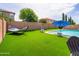Expansive backyard with a hammock, pool, lush synthetic lawn, and shaded seating area at 761 W Desert Hollow Dr, San Tan Valley, AZ 85143