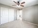 This is a neutral bedroom with carpet flooring, ceiling fan, and built-in closet with white doors at 761 W Desert Hollow Dr, San Tan Valley, AZ 85143