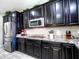 Modern kitchen features black cabinetry, stainless steel appliances, granite countertops, and decorative backsplash at 761 W Desert Hollow Dr, San Tan Valley, AZ 85143