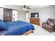 Bright main bedroom with a ceiling fan, dresser with tv, and king bed covered with blue comforter at 761 W Desert Hollow Dr, San Tan Valley, AZ 85143