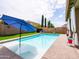 Sparkling pool with umbrella, and patio with turf surrounded by block fence and greenery at 761 W Desert Hollow Dr, San Tan Valley, AZ 85143