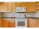 Kitchen features white appliances, stone backsplash, and light wood cabinets at 7707 E Park View Dr, Mesa, AZ 85208
