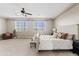 Bright bedroom with a ceiling fan, carpeted floor, large windows, and a cozy armchair at 10331 E Starion Ave, Mesa, AZ 85212