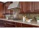 Gourmet kitchen featuring dark wood cabinets, granite countertops, a gas cooktop, and stylish backsplash at 10331 E Starion Ave, Mesa, AZ 85212