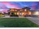 A beautiful backyard with a large grassy area and the house facade under a vibrant dusk sky at 12015 S Tuzigoot Dr, Phoenix, AZ 85044