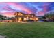 Expansive backyard featuring a lush green lawn and a multi-story home bathed in the warm glow of sunset at 12015 S Tuzigoot Dr, Phoenix, AZ 85044