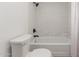 Clean bathroom featuring a white toilet, tub with white tile surround, and black fixtures under bright lighting at 12015 S Tuzigoot Dr, Phoenix, AZ 85044