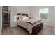 Well-lit bedroom with a wooden bed frame, light wood floors, a large window, and an open closet space at 12015 S Tuzigoot Dr, Phoenix, AZ 85044