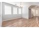 Bright dining room with archway, wood-look tile, chandelier, and many windows at 12041 W Fillmore St, Avondale, AZ 85323