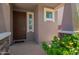 Home entryway with a dark wood door and neutral stucco exterior, flanked with flowering plants at 12041 W Fillmore St, Avondale, AZ 85323