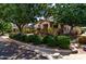 Charming home featuring a cozy front porch framed by lush green trees and manicured bushes at 13602 N 149Th Ave, Surprise, AZ 85379