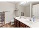 Bathroom with double sinks, wood cabinets, a decorative cabinet, and a shower with colorful curtains at 18542 W Valerie Dr, Surprise, AZ 85374