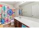 Clean bathroom with a large mirror, wood cabinets, and a colorful shower curtain at 18542 W Valerie Dr, Surprise, AZ 85374