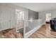 Bright hallway with wood-look floors and white railing with an open view into a bedroom at 18542 W Valerie Dr, Surprise, AZ 85374