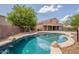 Backyard features a freeform pool with rock details and mature shade trees offering cool retreat at 33055 N Madison Way Dr, San Tan Valley, AZ 85144