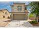 Two-story home with a light beige exterior, a two-car garage, and a well-maintained front yard with green plants at 40345 W Molly Ln, Maricopa, AZ 85138