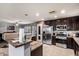 Open kitchen with stainless steel appliances, dark cabinetry, granite countertops, and tile flooring at 40345 W Molly Ln, Maricopa, AZ 85138