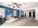 Large living room with a ceiling fan, blue accent wall, neutral carpet, and staircase at 40345 W Molly Ln, Maricopa, AZ 85138