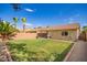 Desert backyard with expansive lawn, desert landscaping, tan block wall, and covered patio at 44976 W Miramar Rd, Maricopa, AZ 85139