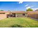 Large grassy backyard with desert landscaping, covered patio, barbecue, and beige block wall at 44976 W Miramar Rd, Maricopa, AZ 85139