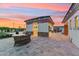 Outdoor patio featuring stone flooring, a covered seating area with outdoor kitchen, and lovely backyard sunset views at 7482 S Mccormick Way, Queen Creek, AZ 85142