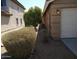 Image shows the side of the house, a neatly landscaped exterior with desert rock and shrubs separating houses at 7771 N 58Th Ln, Glendale, AZ 85301