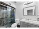 Well-lit bathroom featuring a modern vanity, mirror, toilet, and a shower with a glass door and dark stone-look surround at 858 W Knowles Cir, Mesa, AZ 85210