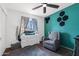 Cozy bedroom with a glider, dresser, teal accent wall, window and neutral carpet creating a calming space at 858 W Knowles Cir, Mesa, AZ 85210