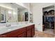 Modern bathroom with double sinks, granite countertops, and a spacious walk-in closet with organized storage at 8788 W Wood Dr, Peoria, AZ 85381
