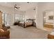 Bright bedroom featuring plantation shutters, ceiling fan, and seating area with luxurious bath in background at 9435 E Hobart Cir, Mesa, AZ 85207