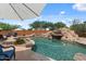 Backyard swimming pool with rock waterfall feature, lounge chairs, and mature landscaping for a private oasis at 9435 E Hobart Cir, Mesa, AZ 85207
