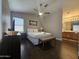 Bedroom with queen bed, ceiling fan, wooden floors, a window, and an adjacent bathroom at 9983 W Monterosa Ave, Phoenix, AZ 85037